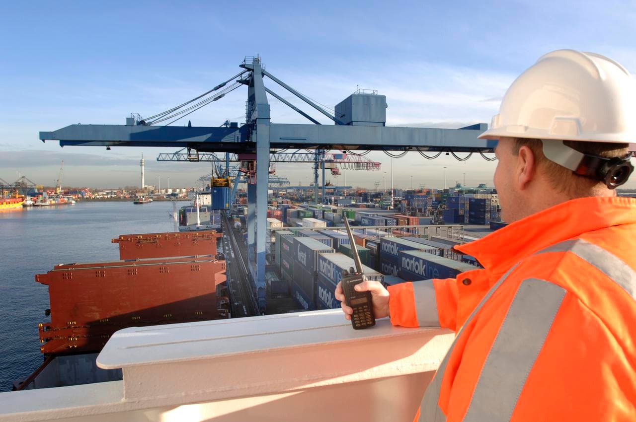 DFDS employee wearing orange vest and construction hat overlooks shipping containers