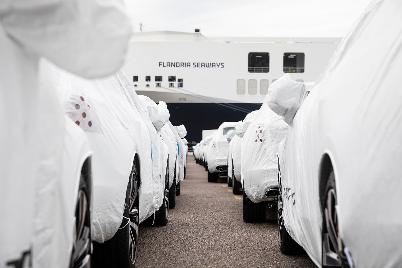 Rows of white cars aligned next to the DFDS freight shipping vessel Flandria Seaways